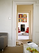 View though two doorways - living room in cool colours contrasting with bright red designer chairs below pop art picture