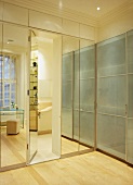 Contemporary fitted cupboards with glass and mirrored fronts and integrated door leading to ensuite bathroom