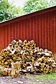 Firewood piled against a wooden wall