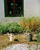 Watering can in garden in front of old house