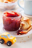 Cranberry jam with a croissant and toy car