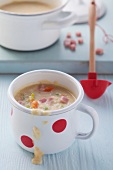 Mug of vegetable soup with cubes of ham