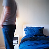 Lady standing next to a bed with blue sheets