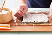 Preparing California rolls: lay cling film over the rice