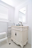 White-painted, antique cabinet in corner of white, renovated bathroom
