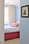 View of bed in bedroom painted light blue through open door