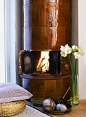 Blick ins lodernde Feuer eines alten Kaminofens und mit hochglänzenden, braunen Fliesen