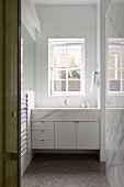 Modern washstand below window in small bathroom