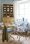 Breakfast table with English garden chairs and old china containers on natural wood shelves