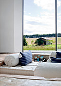 View of old barn across comfortable sunken seating area through floor-to-ceiling panoramic window