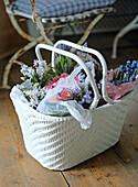 White basket with spring flowers on wooden floor