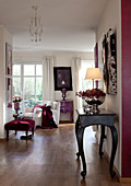 Silver fruit bowl and lamp with lampshade on console table in wide hallway with view into living room