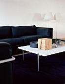 White coffee table in front of a black leather sofa