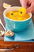 Yellow tomato soup served garnished with flowers