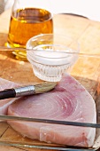 Swordfish steak being brushed with olive oil