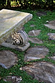 Antique stone bench in the garden and cross sections of tree trunks used as pavers