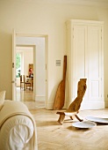 Hand-made, sculptural chair next to bowl on floor in bright, purist room