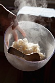 Hand holding a bowl with cooked rice