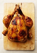 Entire roast chicken on a cutting board (top view)