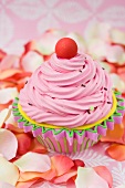 Cupcake with pink butter cream, surrounded by rose petals