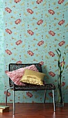 Low chair and decorative pillows in front of floral wallpaper