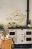 Decorative wall plates above old wood-burning cooker in kitchen