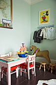 Pink children's chairs and table next to antique rocking horse in child's bedroom