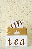 Stacked presents in creative gift wrap in front of wall paper