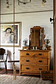 Antique wooden chest of drawers with a mirror in front of a brick wall