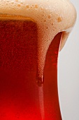Foam Spilling Over the Edge of a Glass of Amber Ale