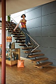 Teenager sliding down banister of modern staircase