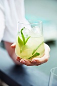 A woman holding a glass of caipirovka with mint