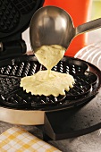 Pouring waffle batter onto a waffle iron