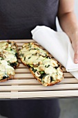 Woman serving bread pizza with mushroom, courgette and cheese