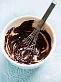 Melted chocolate in a mixing bowl with a whisk