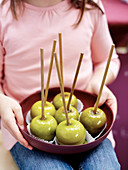 A girl holding a bowl of toffee apples