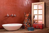 Waschschüssel auf Betontisch vor roter Wand