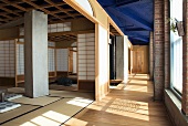 Meditation room with open, Japanese-style sliding wall panels in industrial hall with blue-painted ceiling