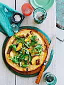 Pizza mit Schweinefleisch, Provolone, Pfirischspalten und Rucola