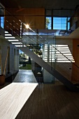 Patterns of light and shade in open-plan stairwell of contemporary house with modern, metal staircase