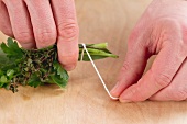 Tying herb stems together with kitchen twine