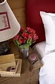 Tulpenstrauss, geschnitzter Handspiegel und plüschiger Lampenschirm auf rustikal antikem Nachttisch