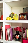 White book shelves with vase of roses, yellow glass eggs and framed family photos