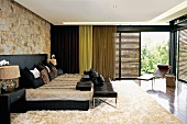 Modern bedroom with animal skin and leather; lounger in front of large, open sliding louvered doors