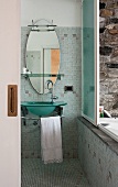 Bathroom with glass sink and oval mirror; sliding window opens to reveal an outdoor bathtub