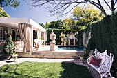 Garten mit antik griechischen Pflanzengefässen vor Pool und Haus mit überdachter Terrasse
