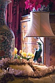 Boudoirausschnitt mit Stehlampe neben bunter Papageienfigur und Barockkommode
