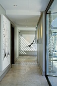 A hallway with a modern black and white painting in a designer house