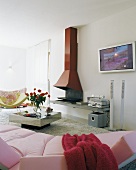 Blick über rosa Sofa auf offenen Kamin mit roter Verkleidung in modernem Wohnzimmer