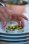 A chef arranging a courgette medley on a plate